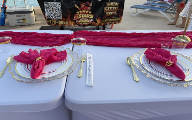 Close-up of a place setting with a pink napkin, gold cutlery and a hand-written name card