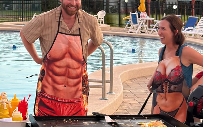 Two guests in novelty aprons standing at the hibachi flat-top beside a resort pool