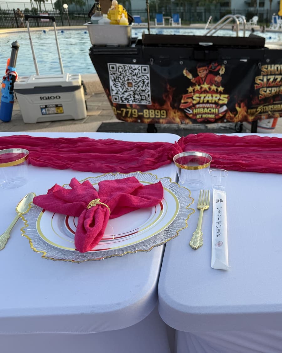 Close-up of a place setting with a pink napkin, gold cutlery and a hand-written name card